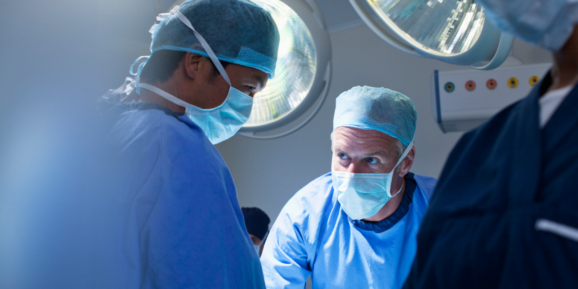 Two male healthcare providers in an operating room setting.