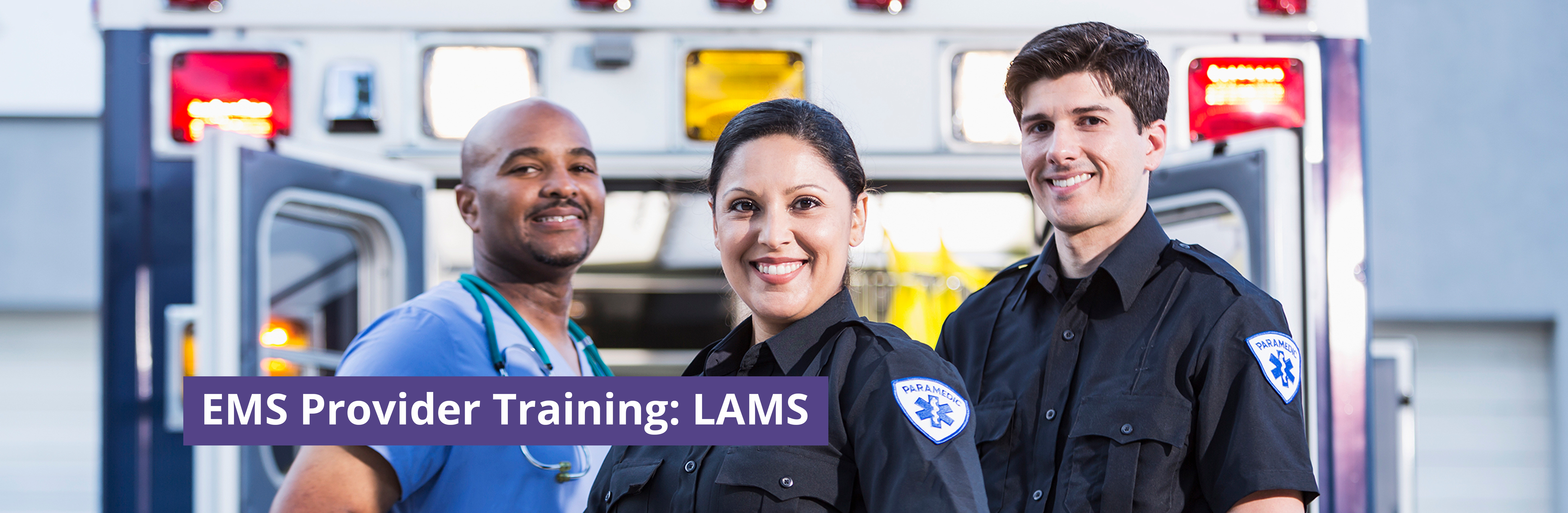 Two paramedics and a clinician stand smiling at the camera in front of an ambulance vehicle.